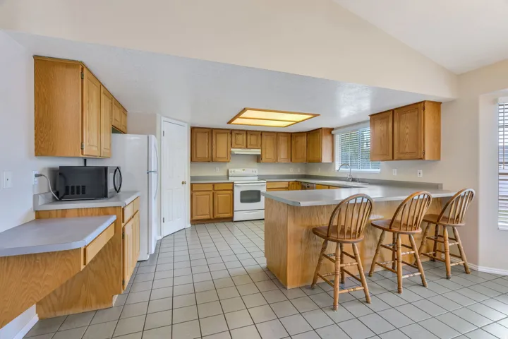 Spacious kitchen featuring extensive cabinetry, tile flooring, a large island with integrated seating, and a built-in oven range