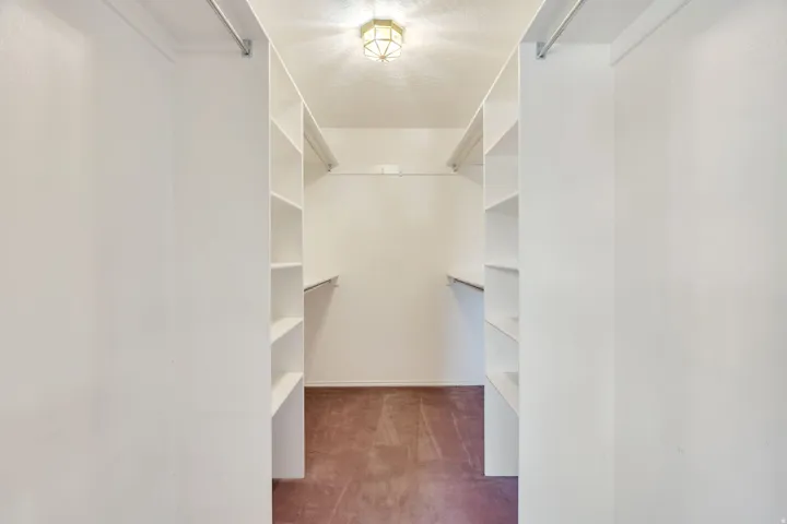 Walk-in closet featuring multiple shelving units, hanging rods, and an overhead light fixture