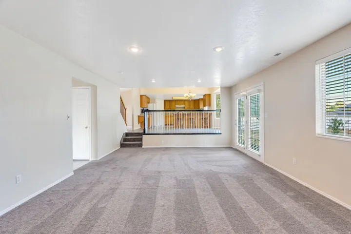 Neutral tone walls, recessed lighting, carpet flooring, patio doors, and a window with blinds