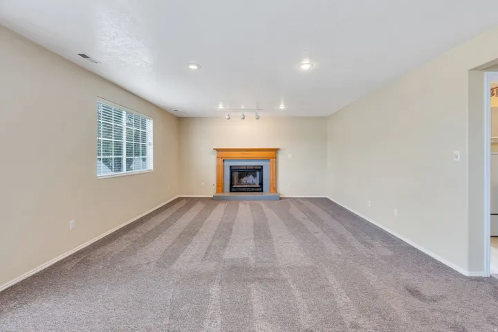 Recessed lighting, window with blinds, carpeted flooring, fireplace with wood mantel, track lighting