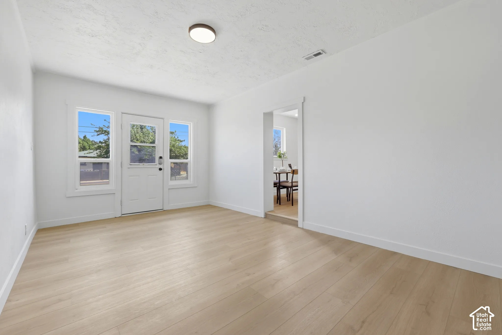 Light wood-finish flooring, white walls, and a flush mount ceiling light