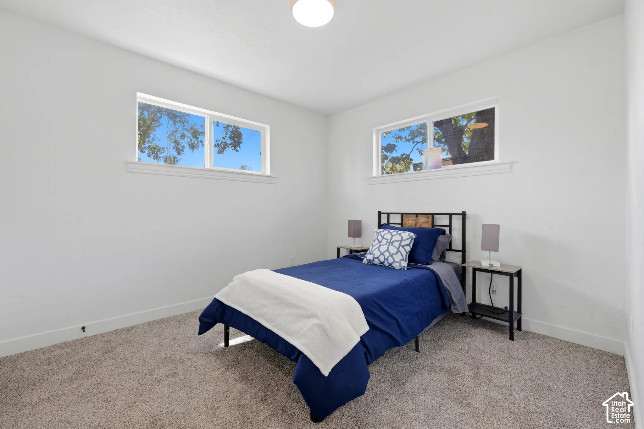 Recessed ceiling lighting, two large windows, white painted walls, and gray carpeting
