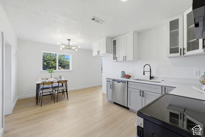 Wood-finish flooring throughout, white walls, double-pane window, modern lighting fixture, and white cabinetry with dark pulls