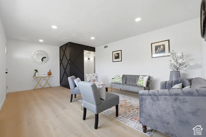 Light wood-finish flooring, recessed lighting, and a textured accent wall