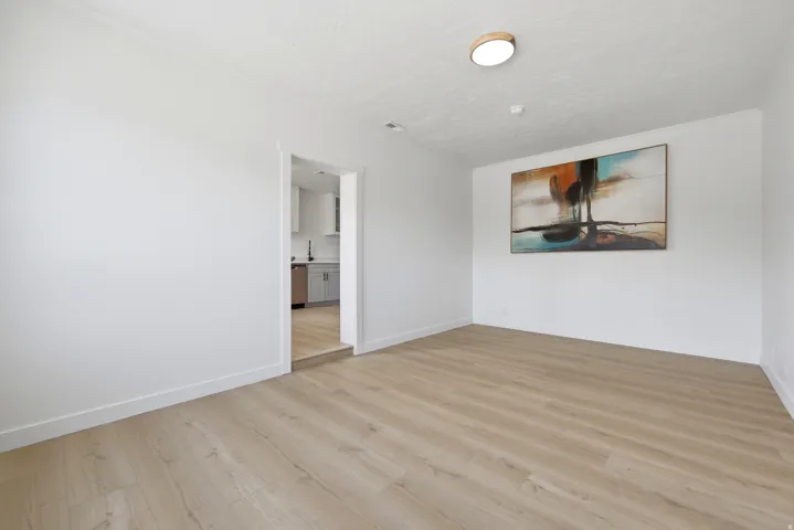 Recessed ceiling light, wood-finish flooring, white walls, and a recessed doorway