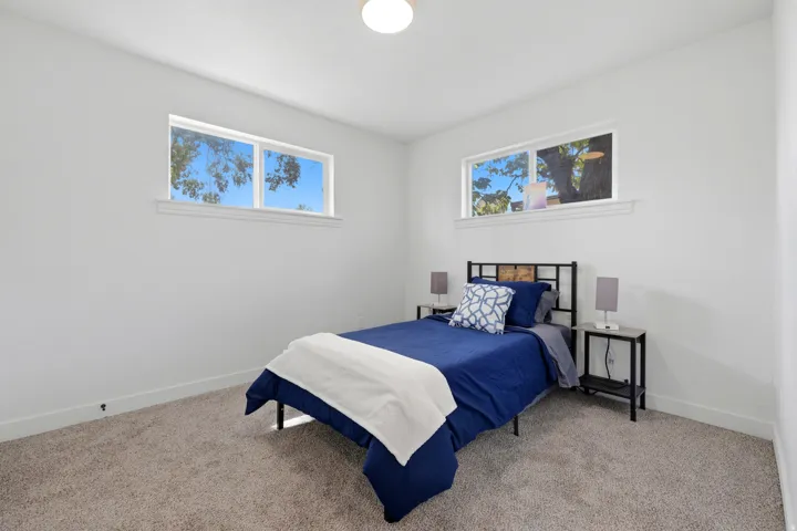Recessed ceiling lighting, two large windows, white painted walls, and gray carpeting