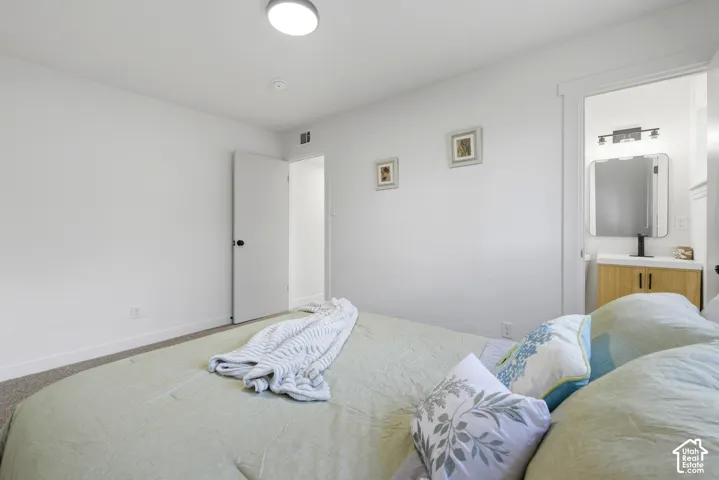 Recessed ceiling light, neutral wall paint, carpeted flooring, white trim details, and a bathroom vanity with a mirror