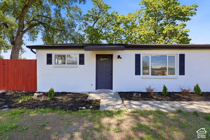 White brick exterior with dark trim and shutters, accented by a deep charcoal entry door