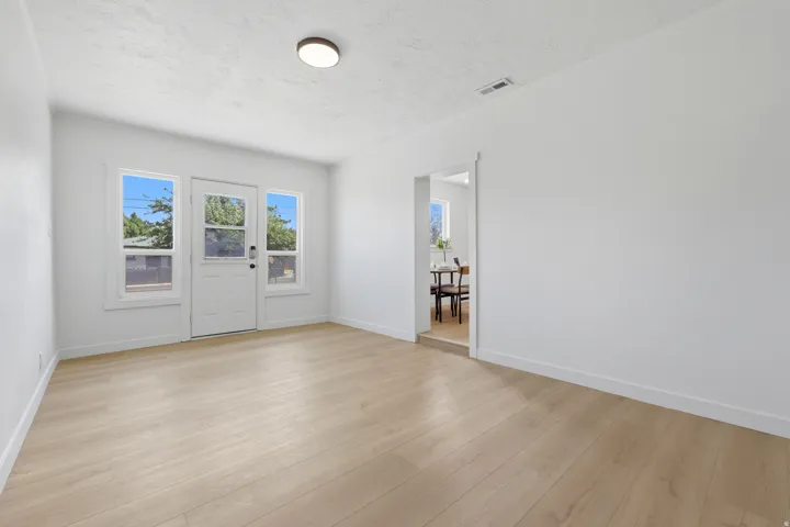 Light wood-finish flooring, white walls, and a flush mount ceiling light