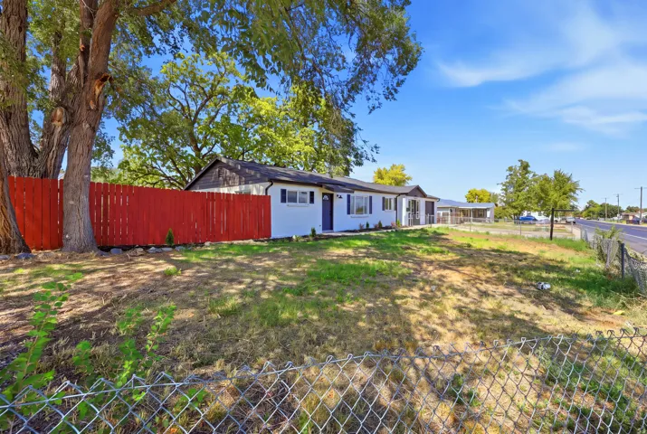 Exterior featuring white siding, a dark roof, and a vibrant red privacy fence