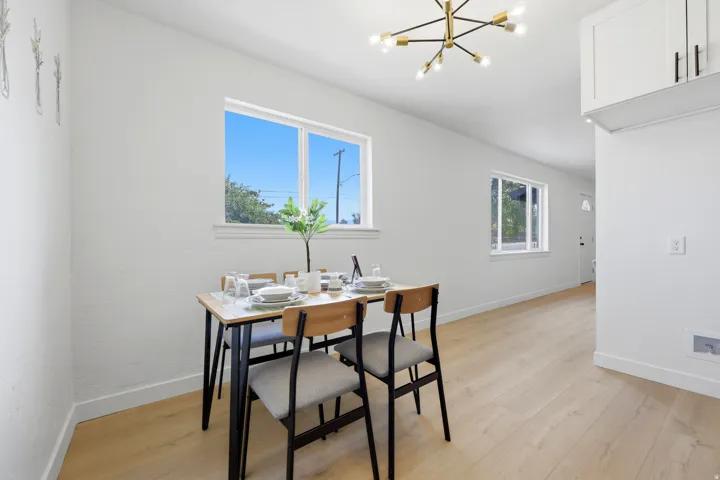 Bright interior with light wood-finish flooring, white walls, and a modern chandelier