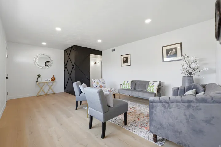Light wood-finish flooring, recessed lighting, and a textured accent wall