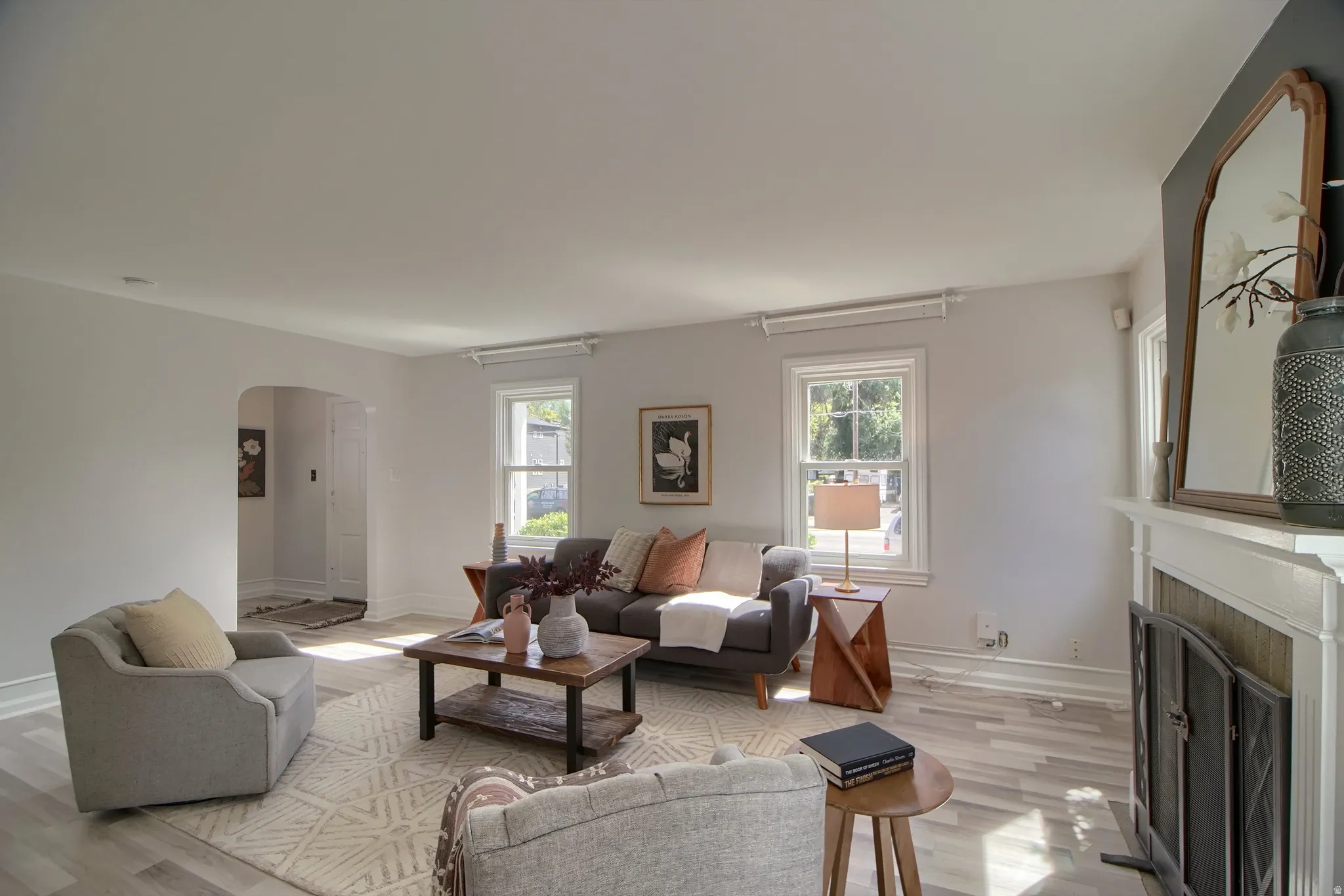 Living area featuring wood-finish flooring, a white mantel, and an arched doorway