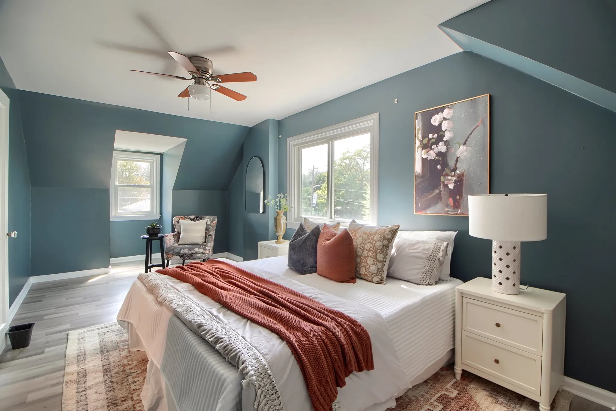 Light wood-finish flooring, crisp white trim, and a ceiling fan with integrated lighting