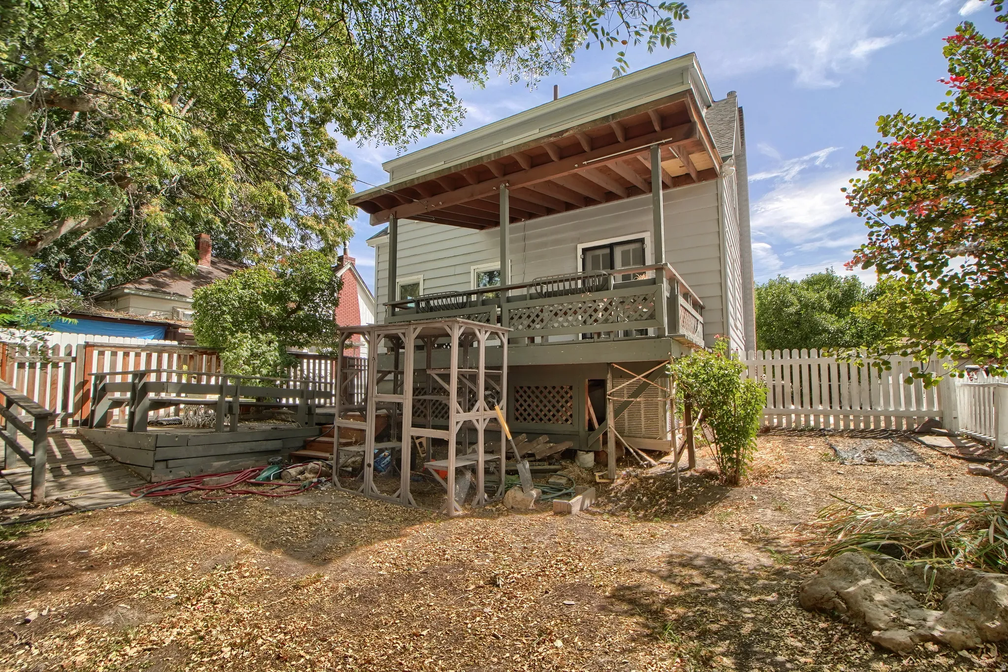 Two-story exterior with a second-level deck, wood fencing, and mature trees