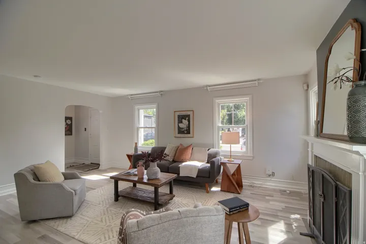 Living area featuring wood-finish flooring, a white mantel, and an arched doorway