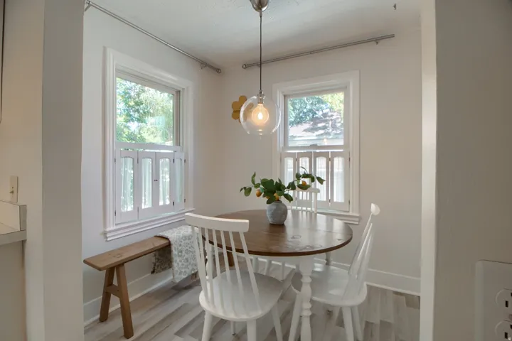 Light wood-finish flooring, white walls, two single-hung windows with white frames, and a clear glass pendant light fixture
