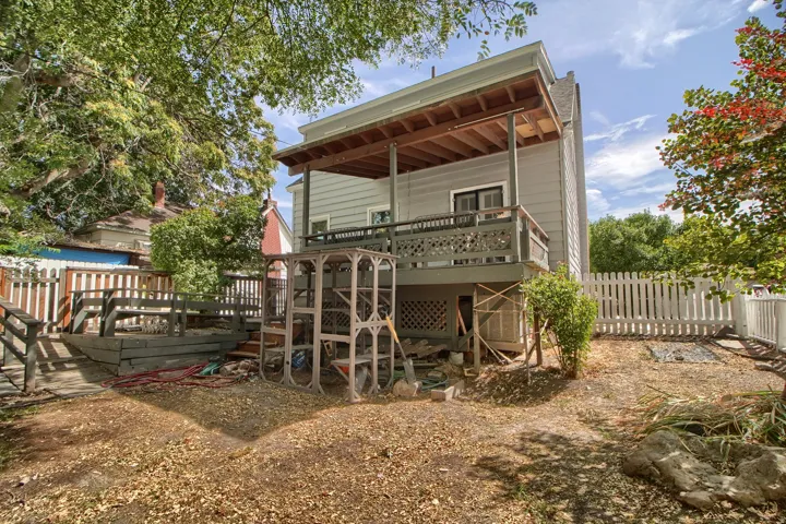 Two-story exterior with a second-level deck, wood fencing, and mature trees