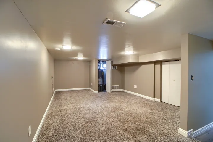 Finished lower level with neutral carpet, recessed lighting, and a utility area