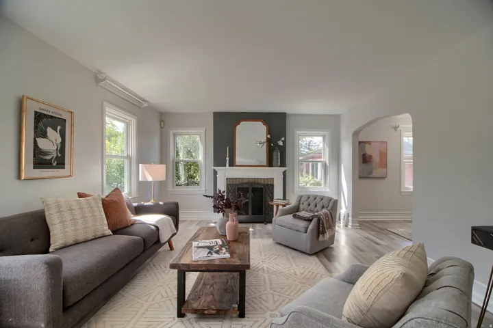 Living area featuring light wood-finish flooring, multiple windows, a decorative fireplace with a mantel, and an arched doorway