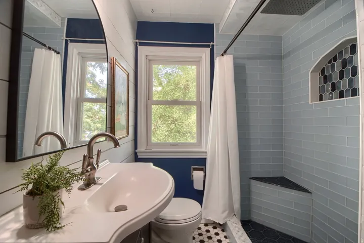 Bathroom featuring a built-in shower niche with mosaic tile, a corner shower bench, and a vanity with an integrated sink