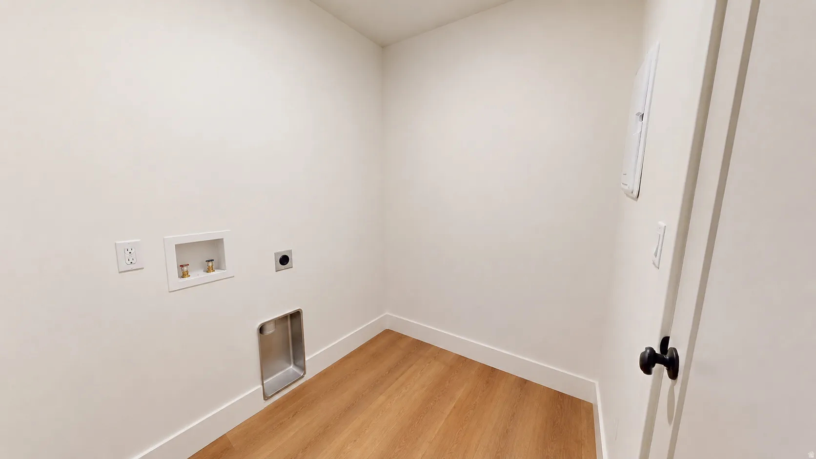 Laundry area featuring wood-finish flooring and electrical outlets