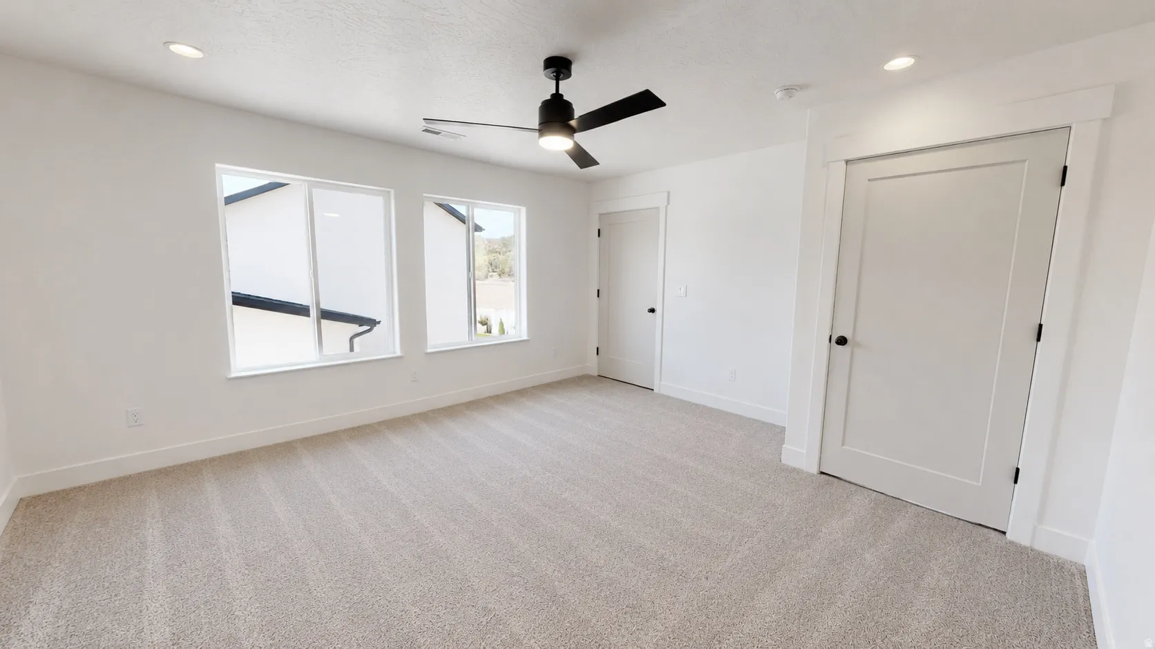 Recessed lighting, light-colored carpeting, and a black ceiling fan