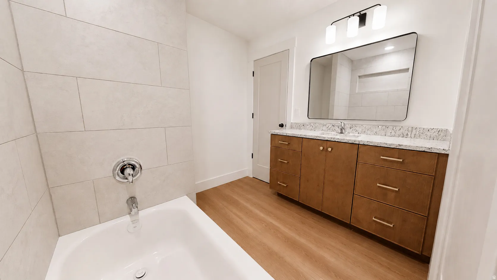 White ceramic bathtub with chrome fixtures and light-toned tile surround