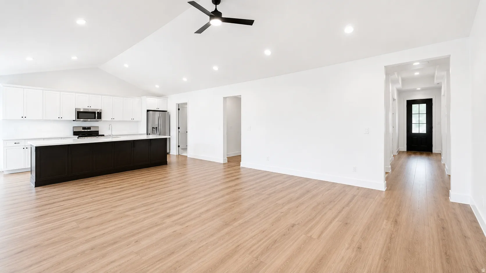 Open-concept living area with wood-finish flooring, vaulted ceiling, and recessed lighting