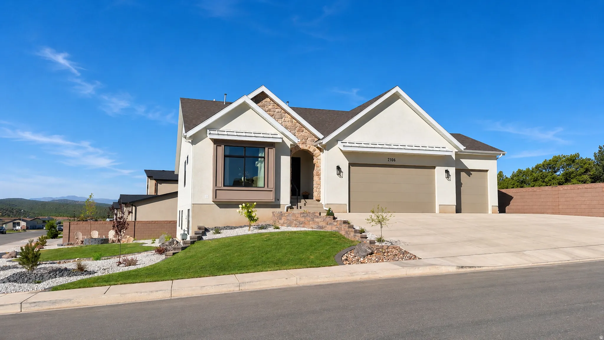 Stucco exterior with stone accents, bay window, three-car garage, and concrete driveway