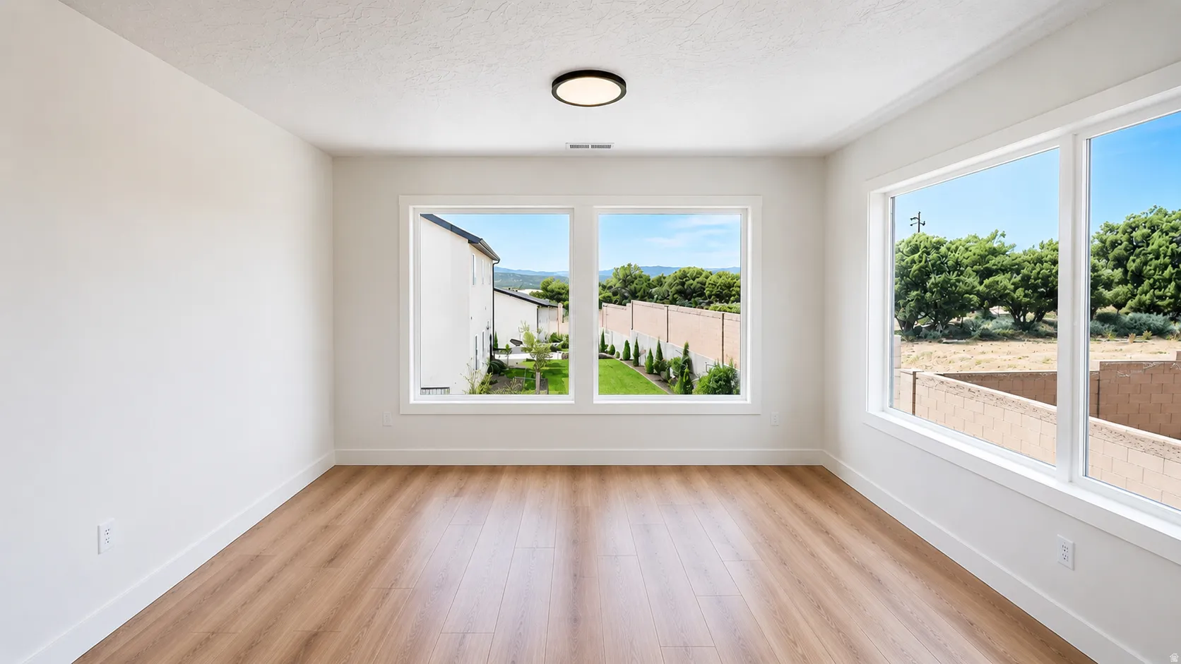 Light wood-finish flooring, white walls, and multiple large windows with white trim