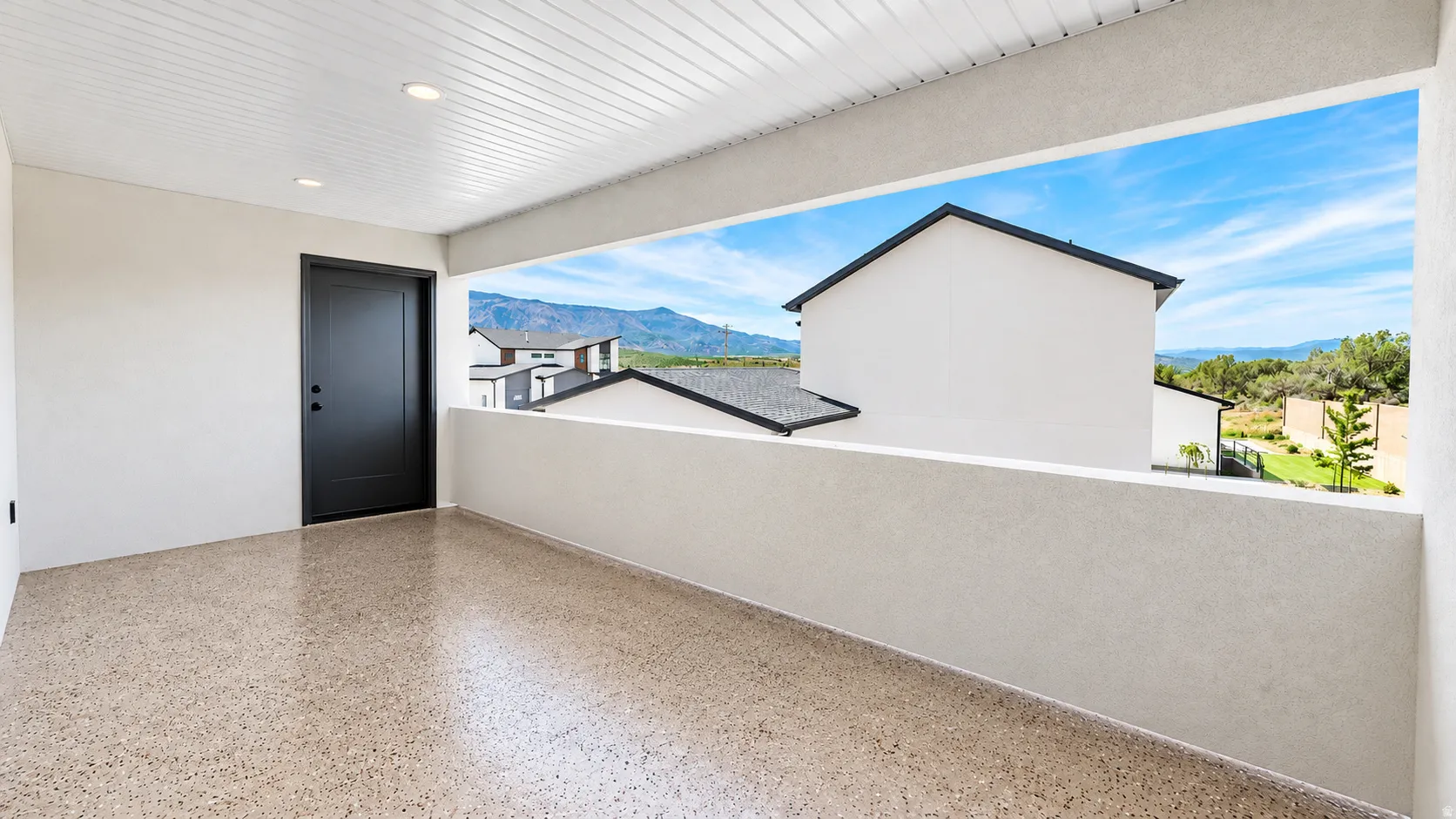 Covered balcony featuring recessed lighting, a solid black entry door, and a durable speckled floor finish