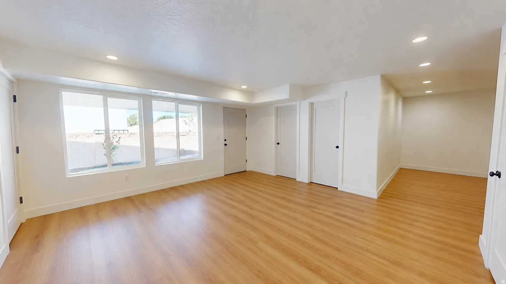 Expansive interior with wood-finish flooring, recessed lighting, and multiple windows