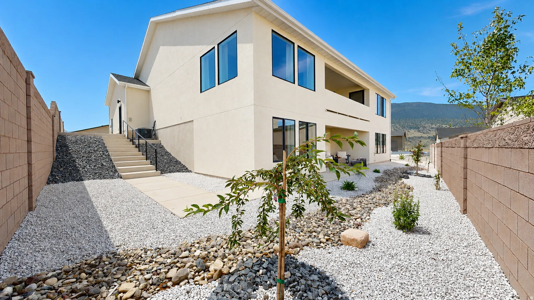Two-story exterior with stucco finish, multiple windows, and a ground-level patio