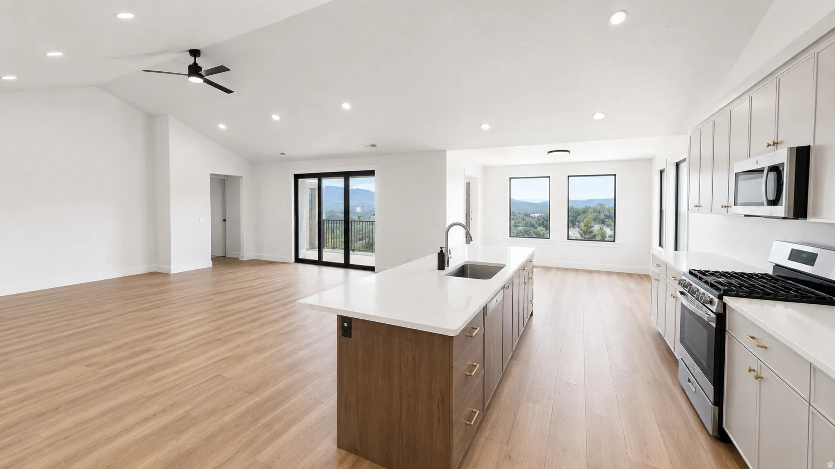 Bright open-concept living space with vaulted ceilings, recessed lighting, and wood-finish flooring