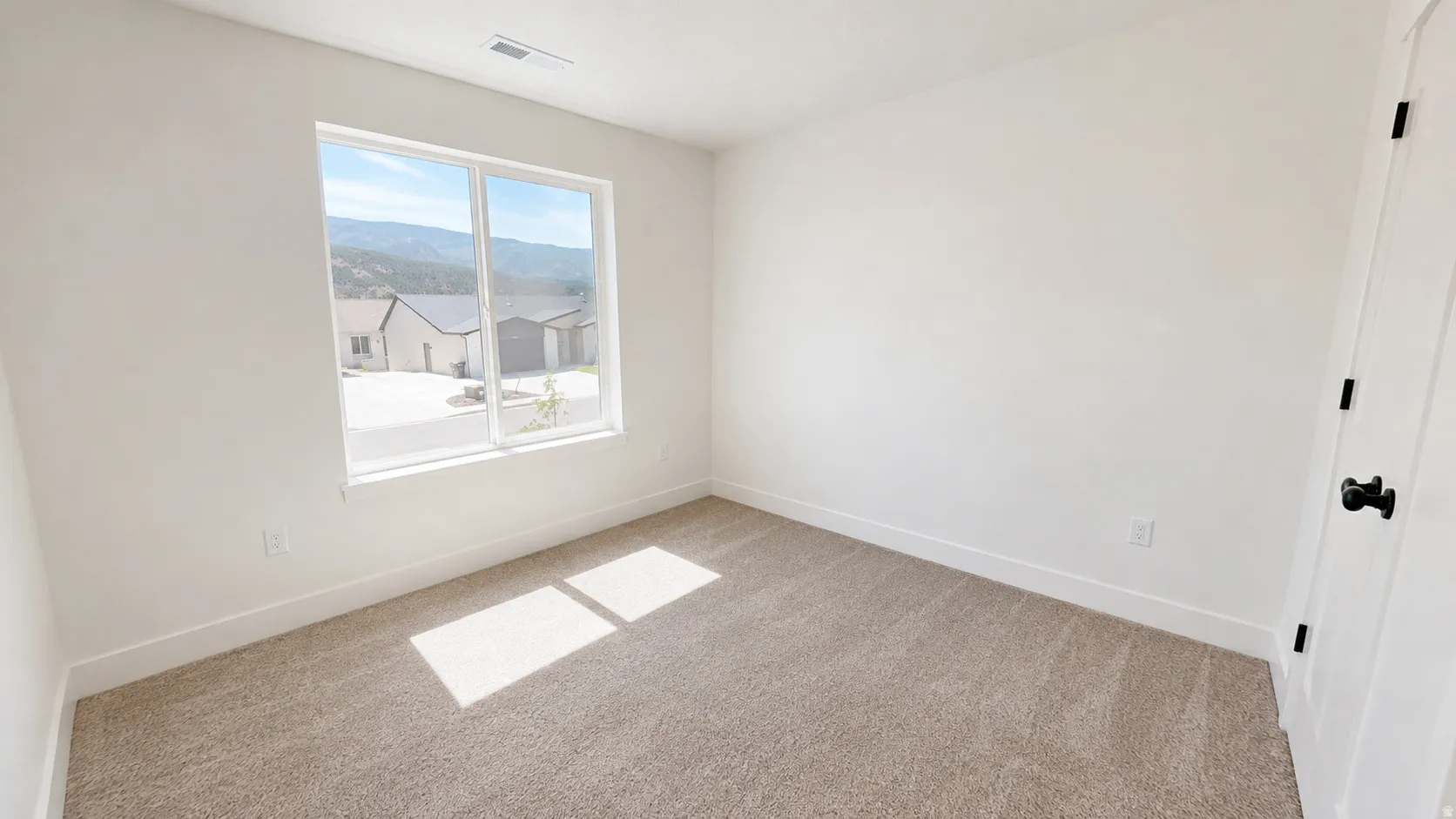 Neutral carpeting, white painted walls, and a white interior door with matte black hardware