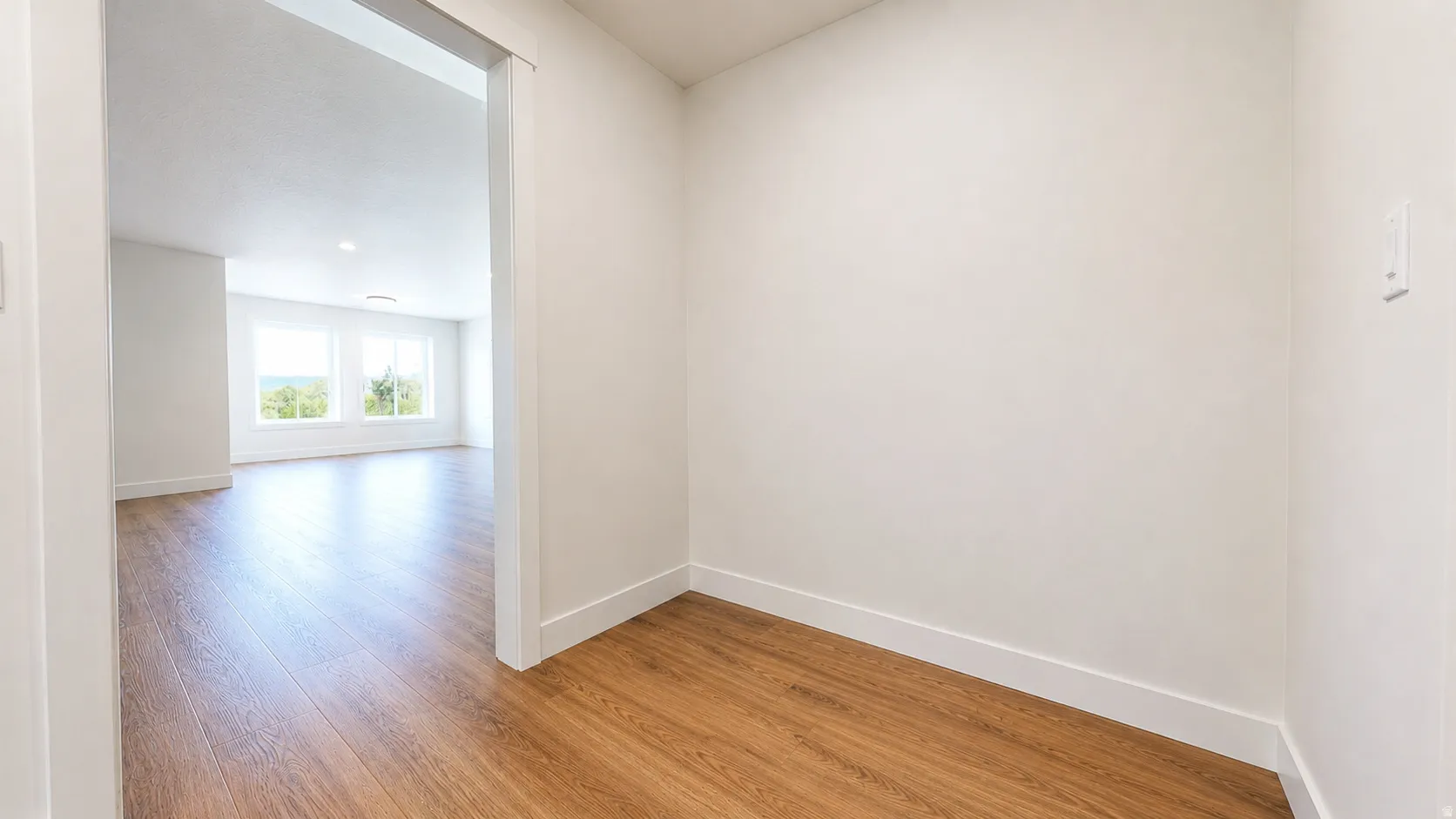 Wood-finish flooring throughout, white wall finishes, and recessed ceiling lighting