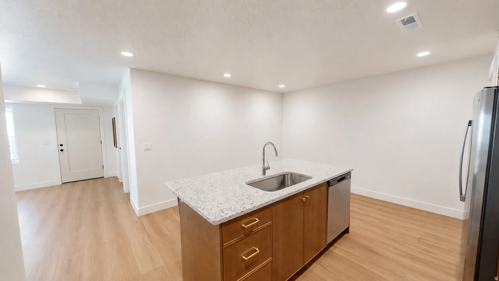 Kitchen island with granite-style countertop, undermount stainless steel sink, and stainless steel dishwasher