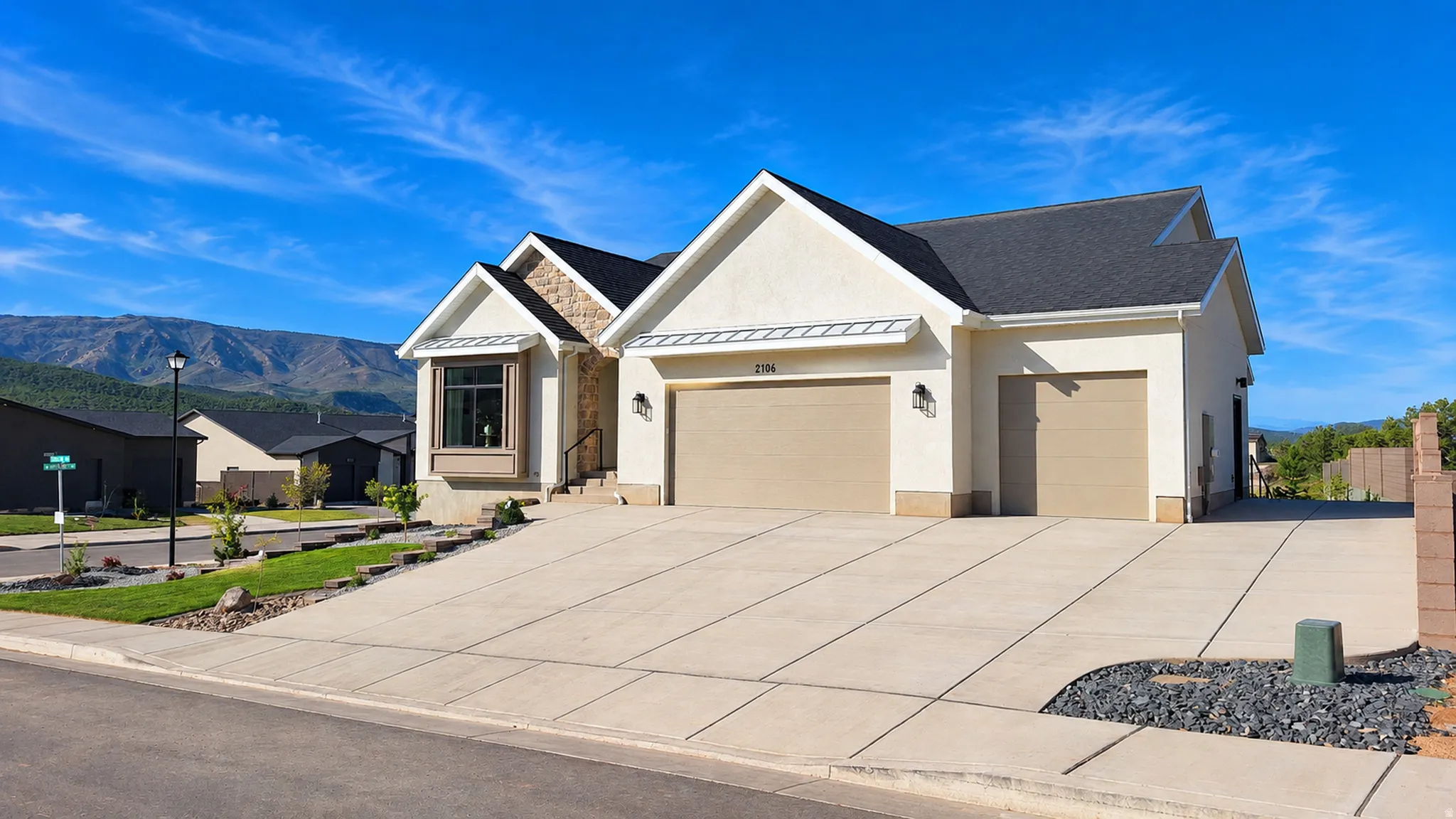 Exterior featuring a two-car garage, stucco siding, stone accents, and a bay window