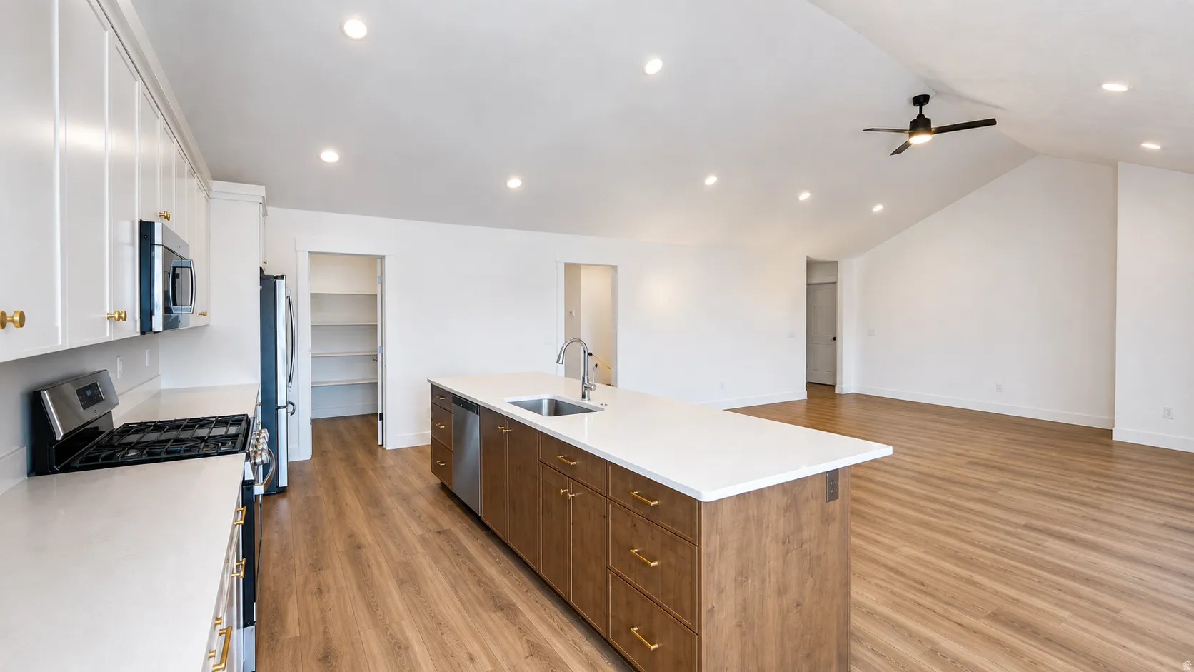 Open-concept living space featuring wood-finish flooring, recessed lighting, and a vaulted ceiling with a ceiling fan