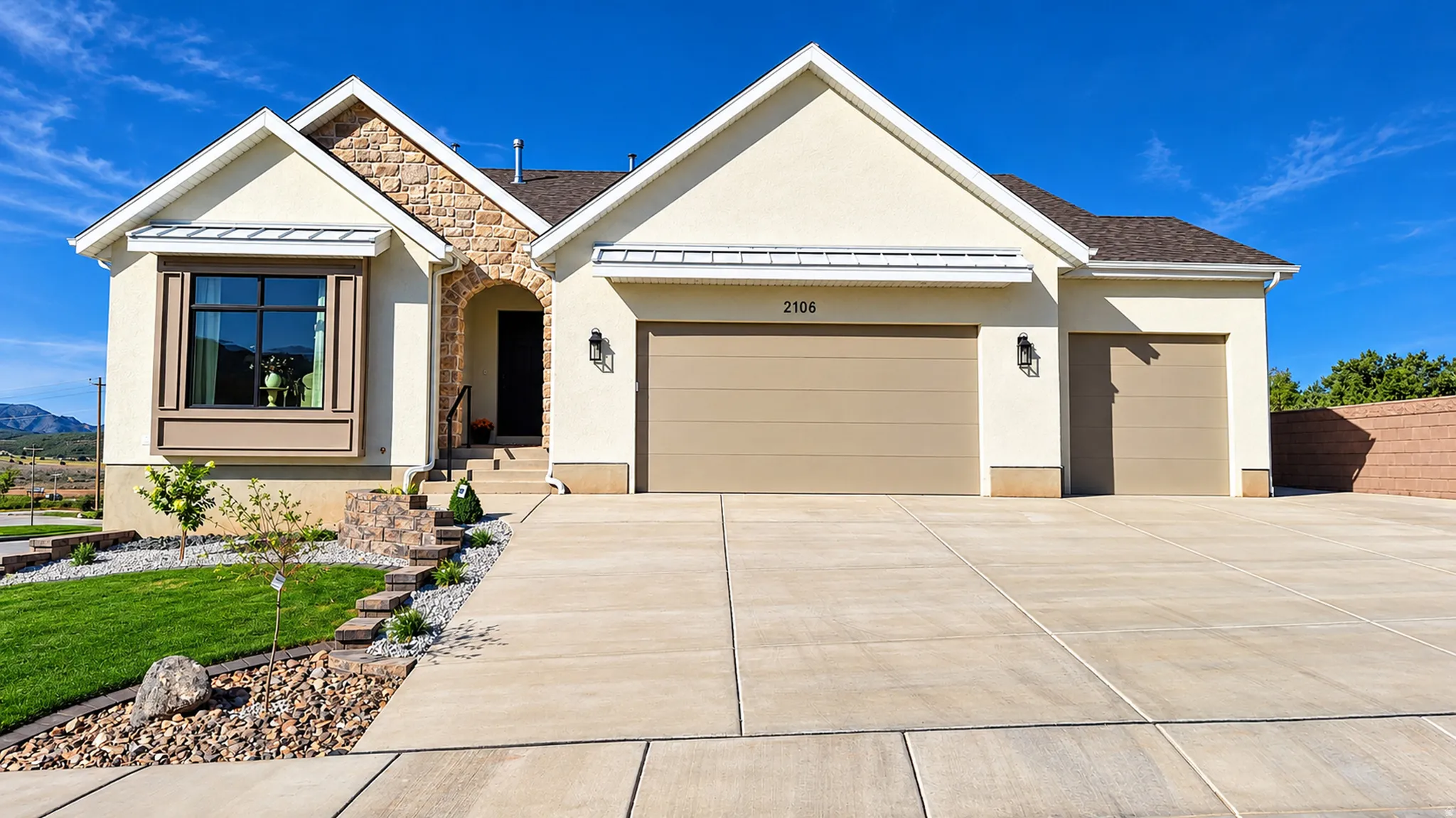 Stucco exterior with stone accents, bay window with shutters, arched entry, and an attached two-car garage