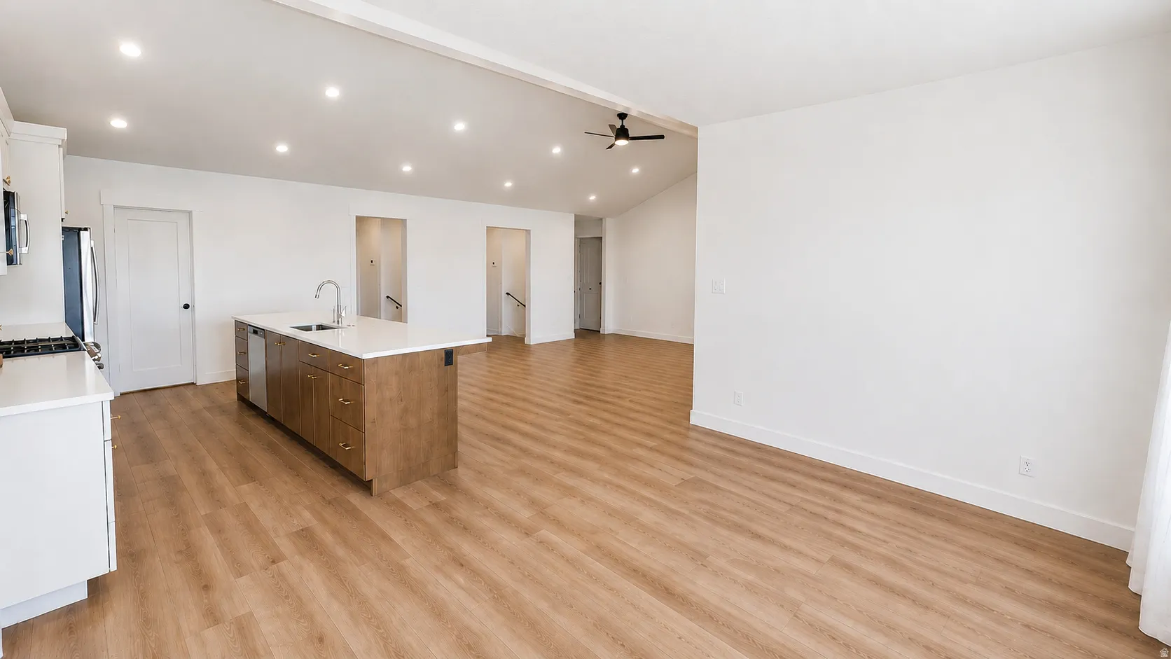 Open-concept living area featuring wood-finish flooring, recessed lighting, and a vaulted ceiling