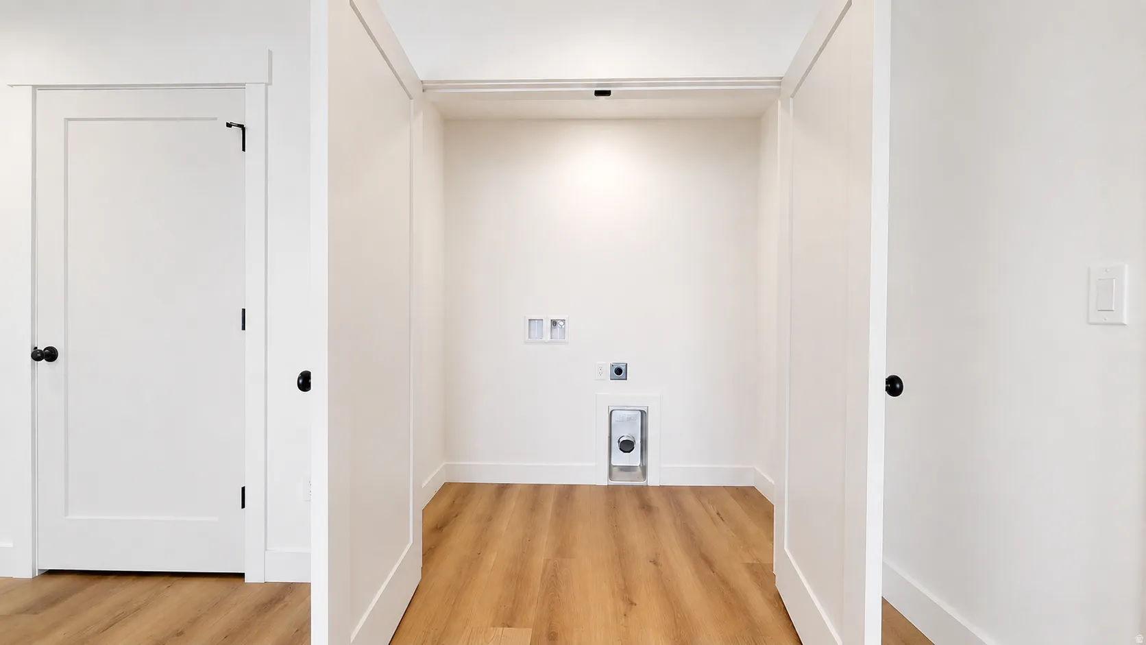 Dedicated utility space featuring wood-finish flooring, white walls, and built-in connections