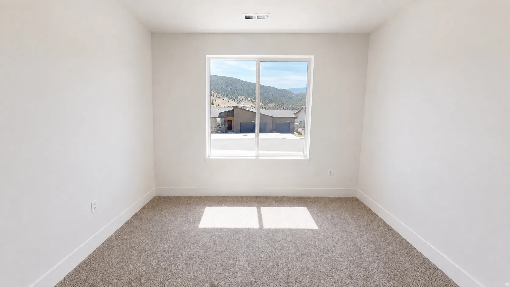 Recessed window with a mountain backdrop, neutral carpeting, and white walls