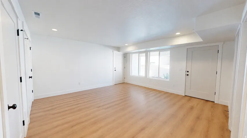 Recessed lighting, wood-finish flooring, multiple white paneled doors, and a series of windows