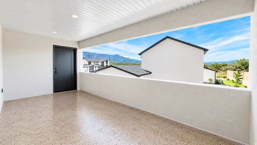 Covered balcony featuring recessed lighting, a solid black entry door, and a durable speckled floor finish