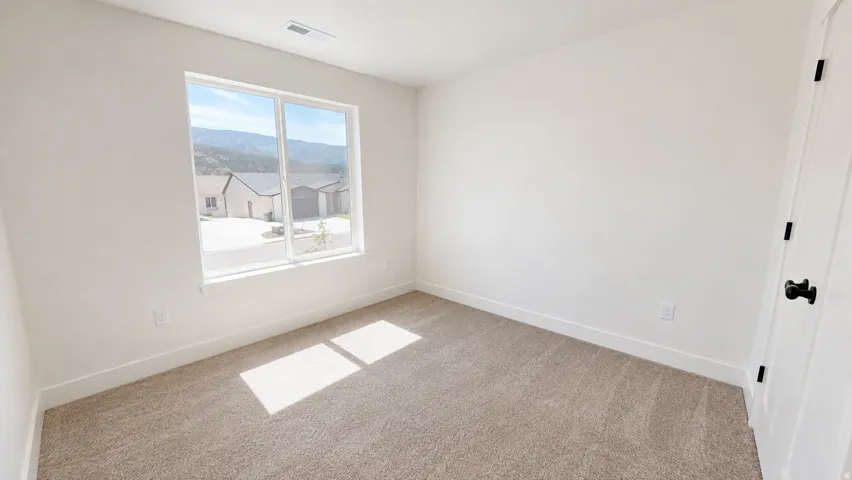 Neutral carpeting, white painted walls, and a white interior door with matte black hardware