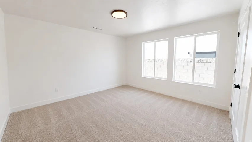 Light-toned carpet flooring, white walls, two white-framed windows, and a flush-mount ceiling light