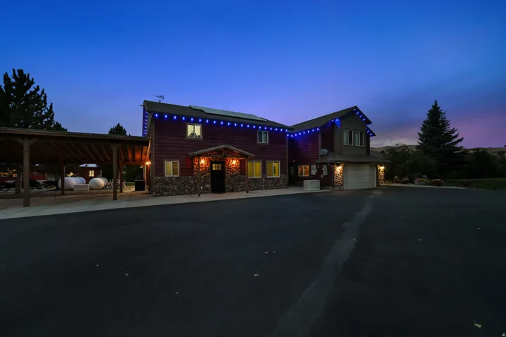 Two-story property featuring wood siding and stone accents, an attached garage, a covered carport, and solar panels