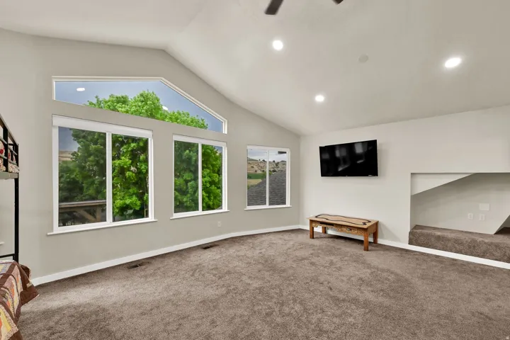 Vaulted ceiling with recessed lighting, large picture windows, and wall-mounted television